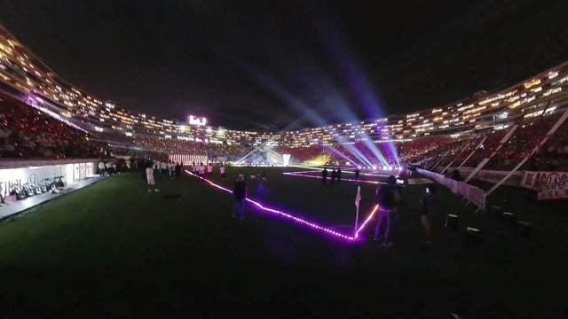 Vista aérea del Estadio Monumental de Lima desde un dron con fuegos artificiales y 40,000 espectadores, con el campo y las gradas iluminados por mini píxeles y túneles de tubos LED, que crean un espectáculo de luz y color