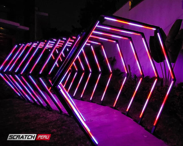 Túnel LED hexagonal multicolor: Efectos luminosos espectaculares en el camino hacia un evento, con luces cambiantes y vibrantes.