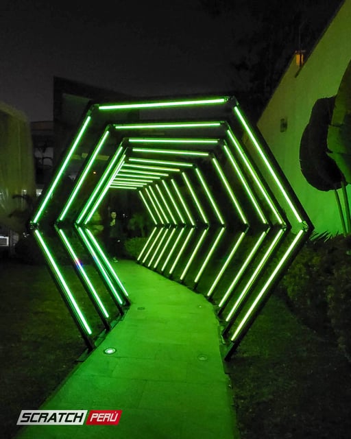 Túnel LED hexagonal verde: Elegante iluminación en el camino hacia una casa de eventos, creando una atmósfera única.