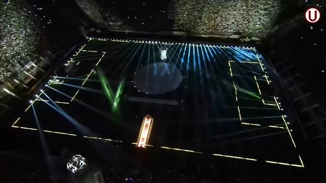 Vista aérea de un estadio de fútbol captada desde un dron, con el campo y las gradas iluminados por mini píxeles y túneles de tubos LED, que crean un espectáculo de luz y color