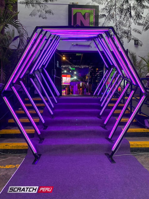Túnel LED hexagonal violeta: Entrada encantadora en escaleras hacia un evento, con iluminación violeta cautivadora.