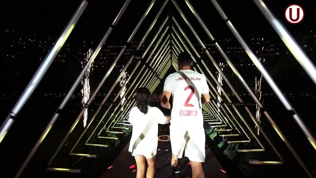 Vista desde el interior de un túnel de tubos LED por el que pasa un jugador de fútbol, con los tubos LED creando un efecto de túnel infinito y una iluminación dramática