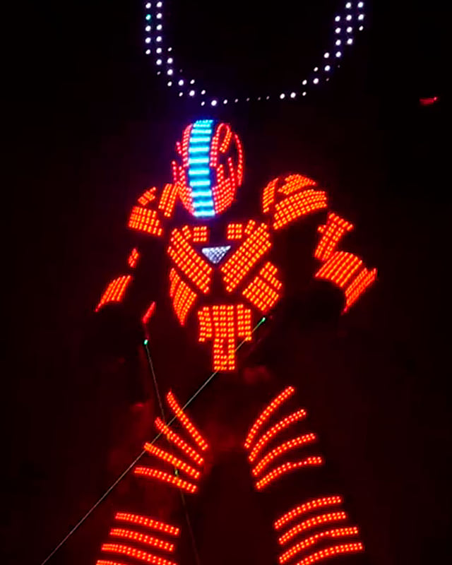Bailarín Lightman con traje LED naranja y casco iluminado