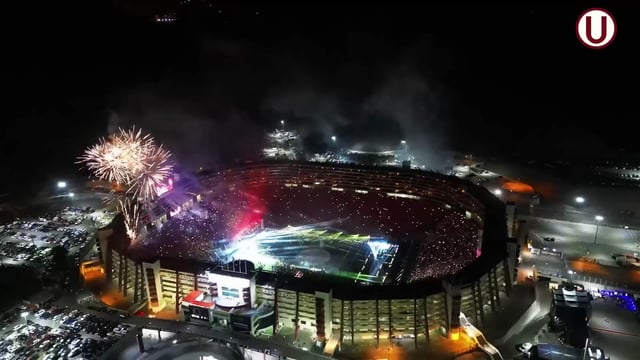 Vista desde el campo de fútbol de usuarios usando brazaletes inalámbricos luminosos en un evento deportivo, con los brazaletes creando un efecto de ola de luz y color en las gradas