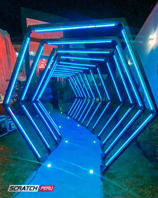 Túnel LED hexagonal azul: Iluminación impresionante en el camino hacia una casa de eventos, creando un ambiente cautivador.