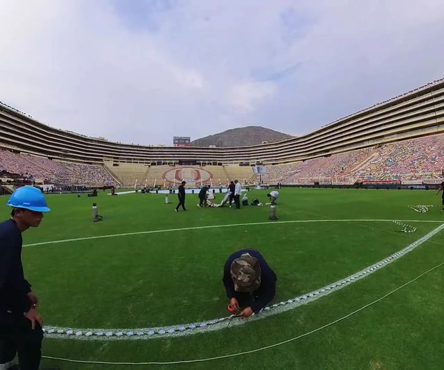 Vista desde las gradas de la cancha de fútbol iluminada en color morado, con los mini píxeles controlados en tiempo real para crear un ambiente festivo y moderno