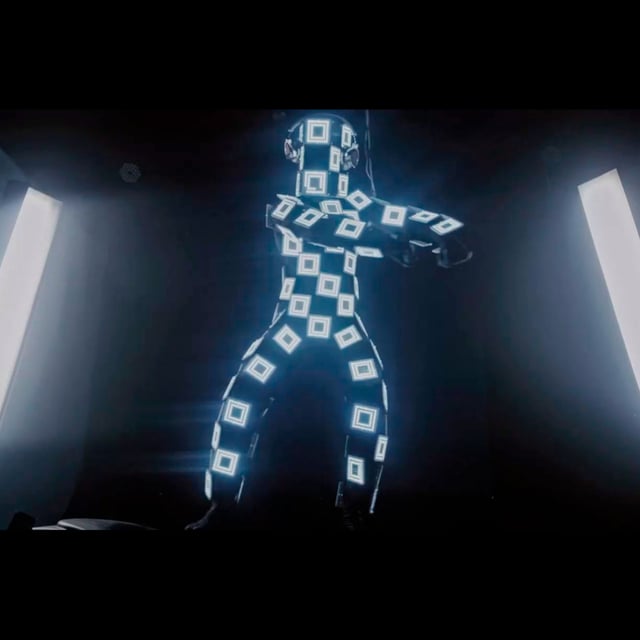 Bailarín Binarman con traje LED de cuadros entre columnas de luz