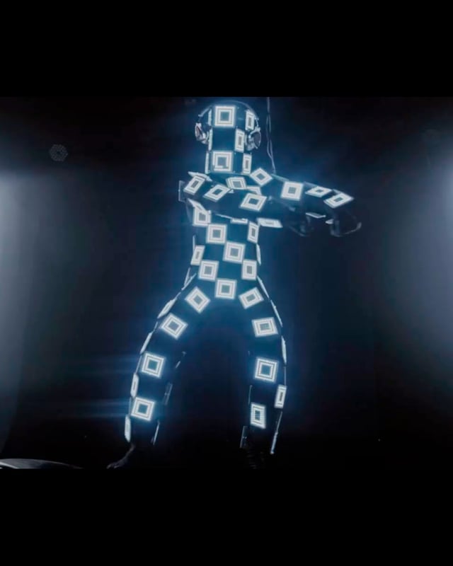 Bailarín Binarman con traje LED de cuadros entre columnas de luz