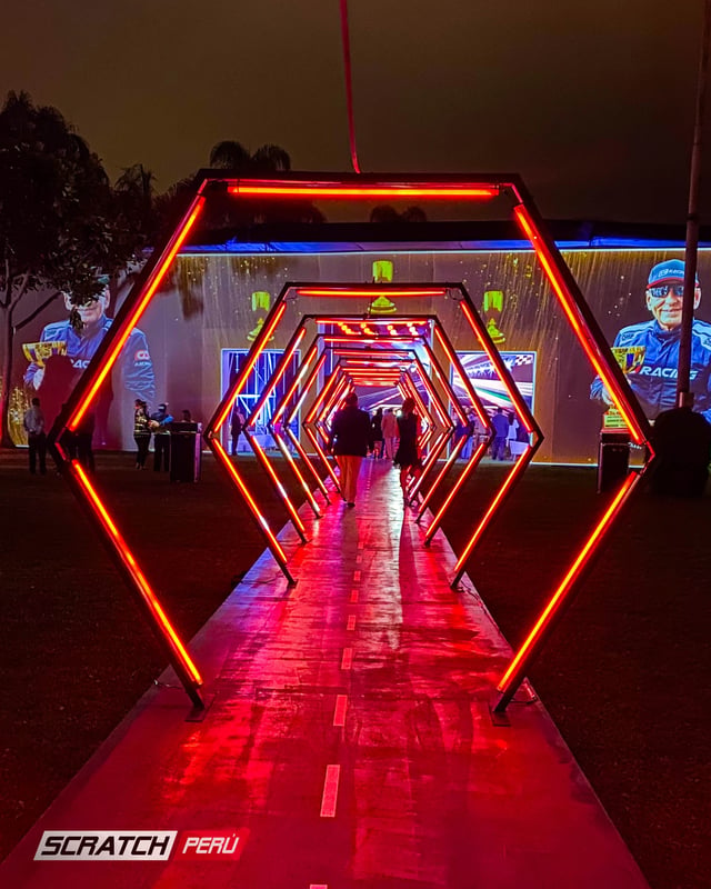 Túnel LED hexagonal rojo: Entrada dramática con personas ingresando al evento, capturando momentos memorables.