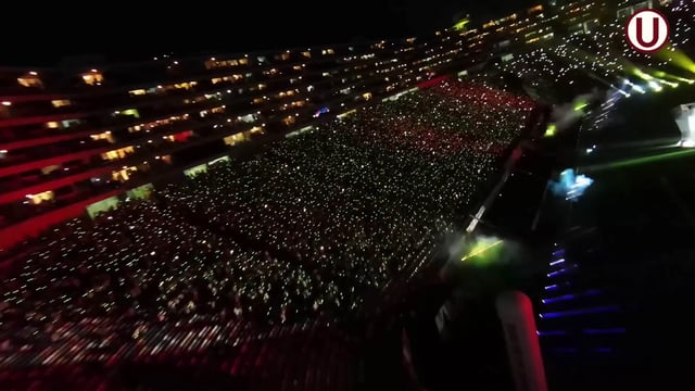 Vista panorámica de un estadio de fútbol lleno de espectadores que llevan pulseras LED DMX inalámbricas de diferentes colores, controladas en tiempo real para crear efectos visuales impresionantes